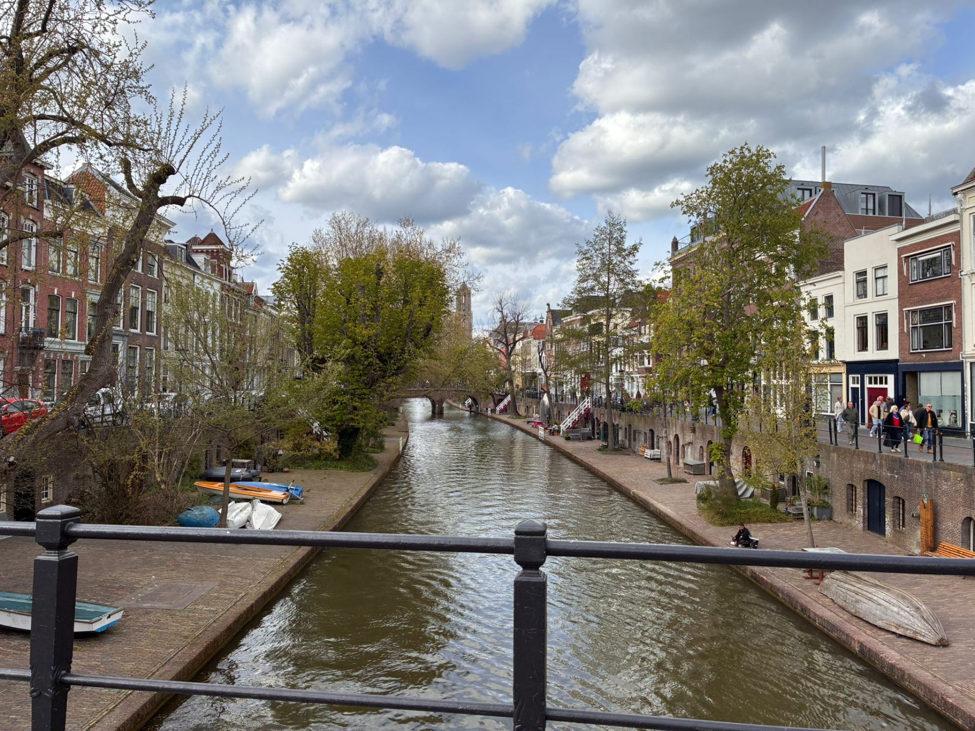 View along the Oudegracht in Utrecht from a bridge, with historic wharf cellars, spring trees and the Dom Tower in the distance