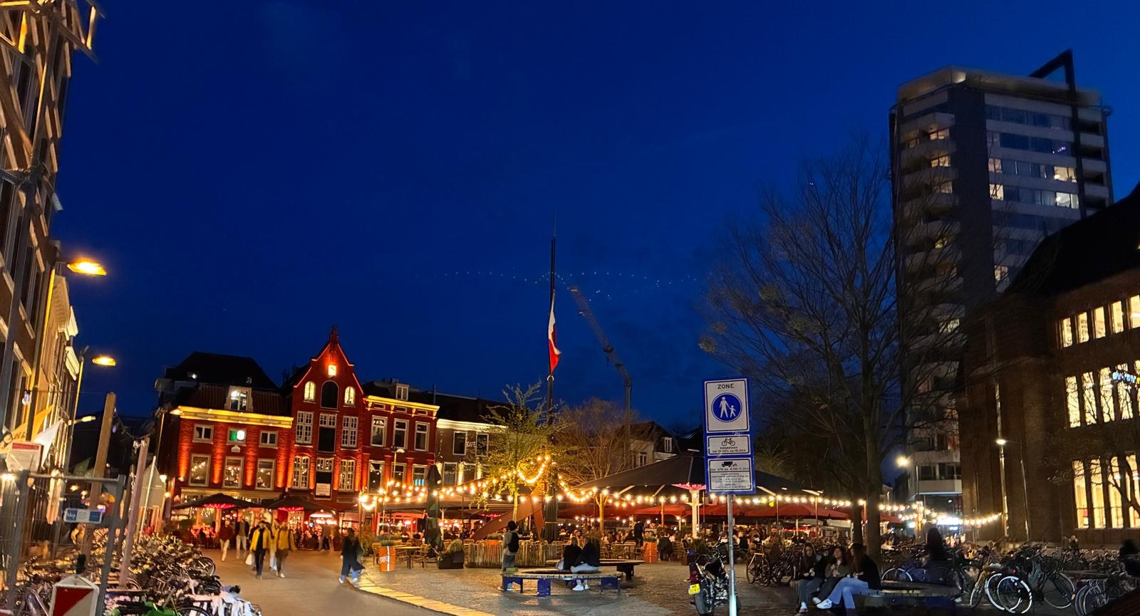 Neude square in Utrecht at dusk with busy restaurant terraces, string lights and people enjoying the evening